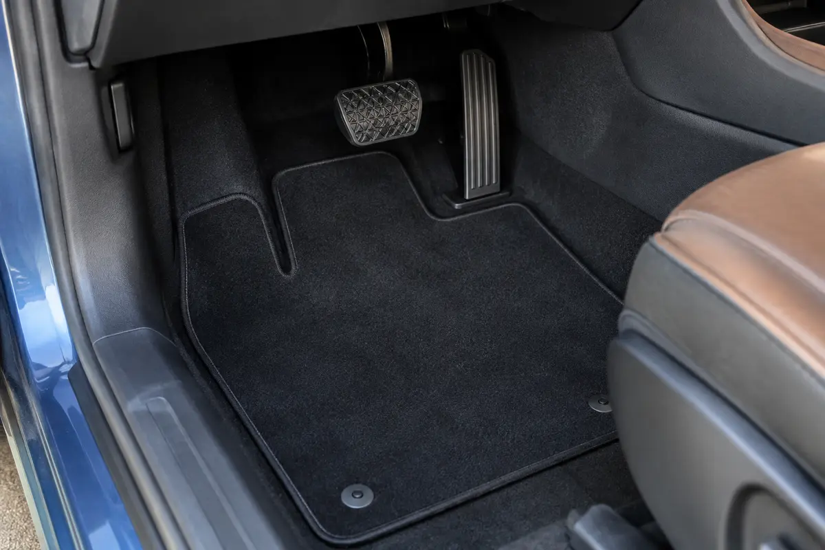 Tapis de sol noir bien fixé dans le plancher conducteur, avec les pédales entièrement dégagées.