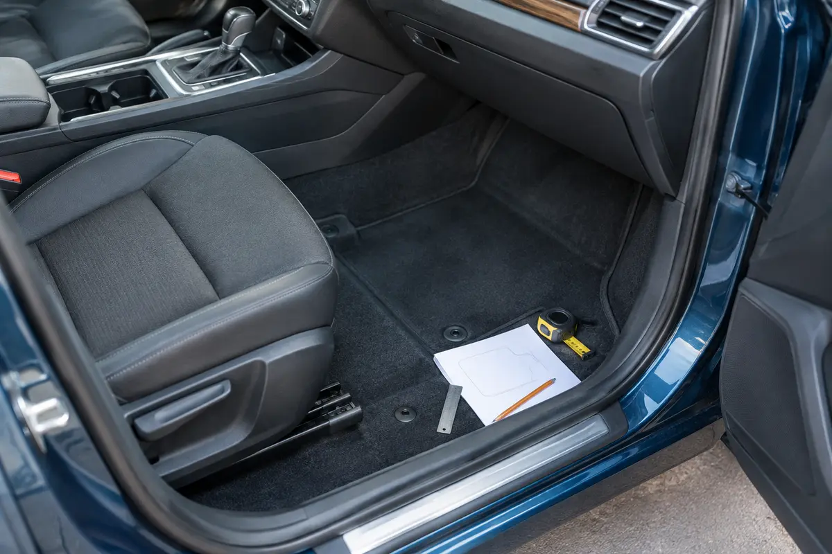 Plancher avant dégagé avec outils de mesure posés à distance des pédales et des garnitures.