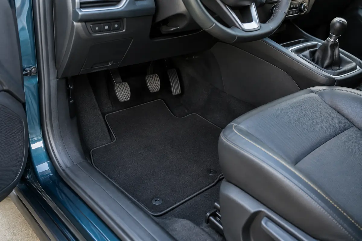 Tapis universel posé dans un habitacle, avec fixations alignées et pédales entièrement dégagées