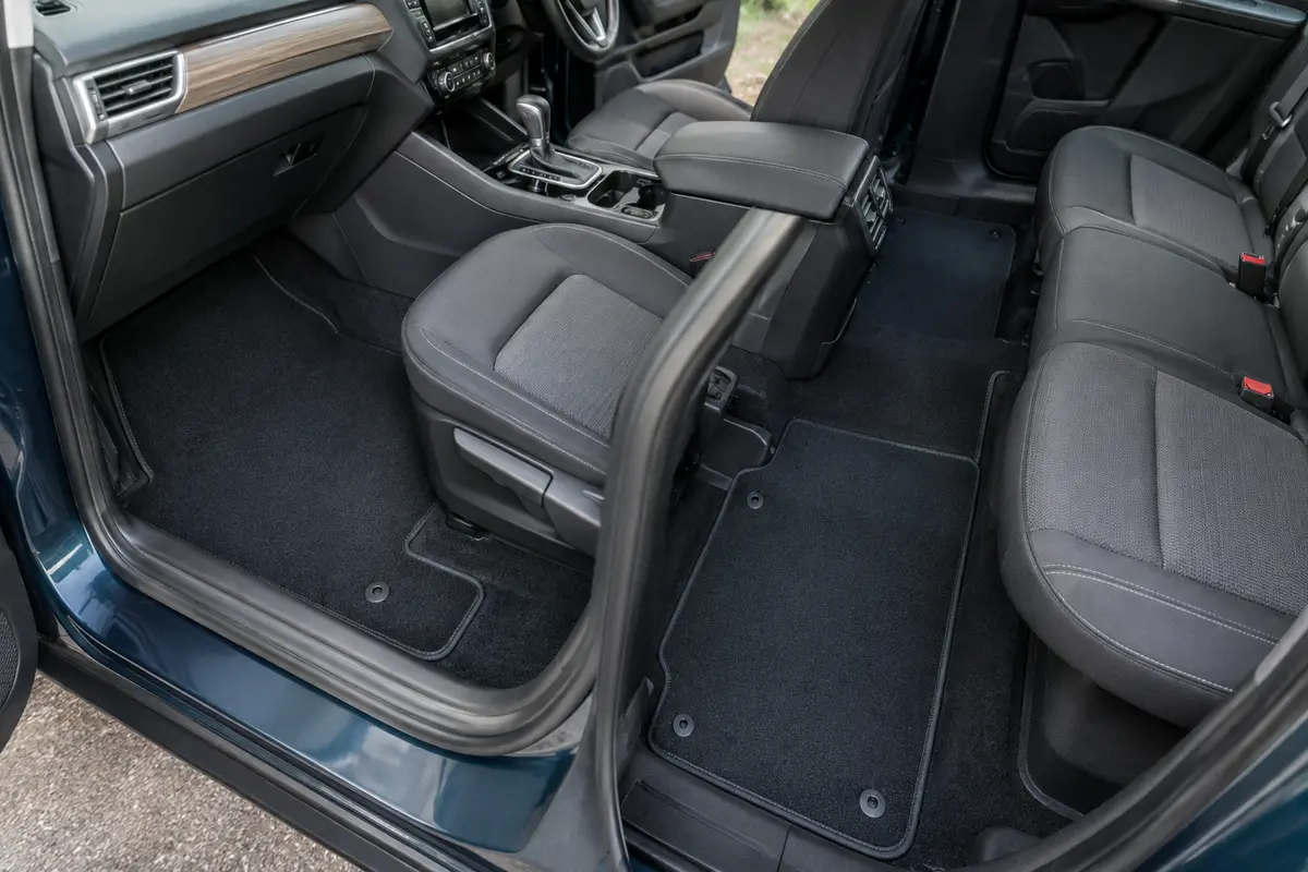 Tapis auto ajustés dans un habitacle, avec le tunnel central et les fixations visibles