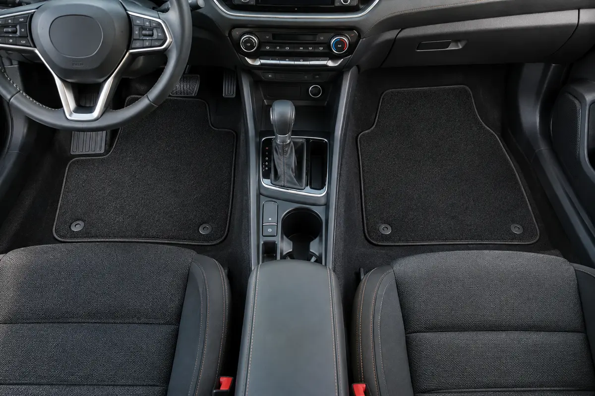 Quatre tapis auto noirs à finition textile installés dans l’habitacle propre d’une voiture compacte.