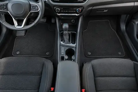 Quatre tapis auto noirs à finition textile installés dans l’habitacle propre d’une voiture compacte.