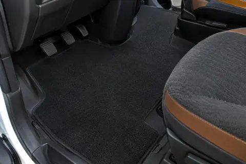 Jeu de tapis noirs en velours textile posé dans la cabine deux places d’un camping-car.