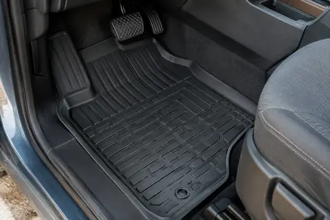 Tapis avant noir en caoutchouc à rebords relevés installé dans l’habitacle d’un utilitaire