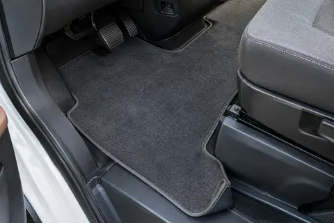 Tapis individuel en velours gris avec bordure effet nubuck posé sur le plancher d’un camping-car