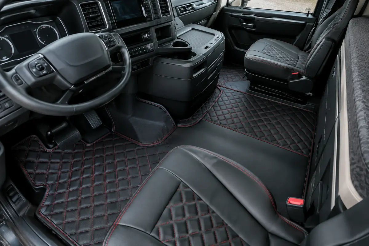 Tapis d’habitacle noirs matelassés avec broderies rouges dans la cabine propre d’un camion