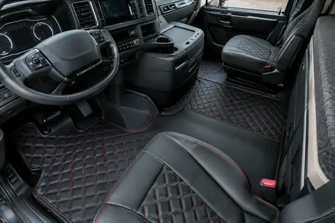 Tapis d’habitacle noirs matelassés avec broderies rouges dans la cabine propre d’un camion