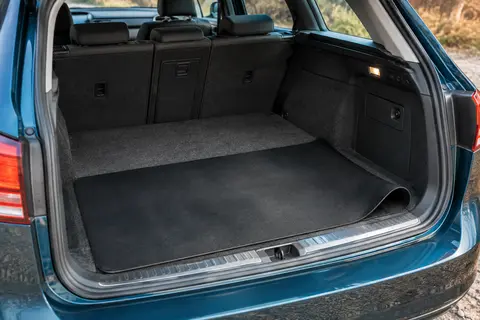Tapis allongé en PVC noir mince, posé en travers d’un coffre de break contre le seuil, une extrémité légèrement enroulée.