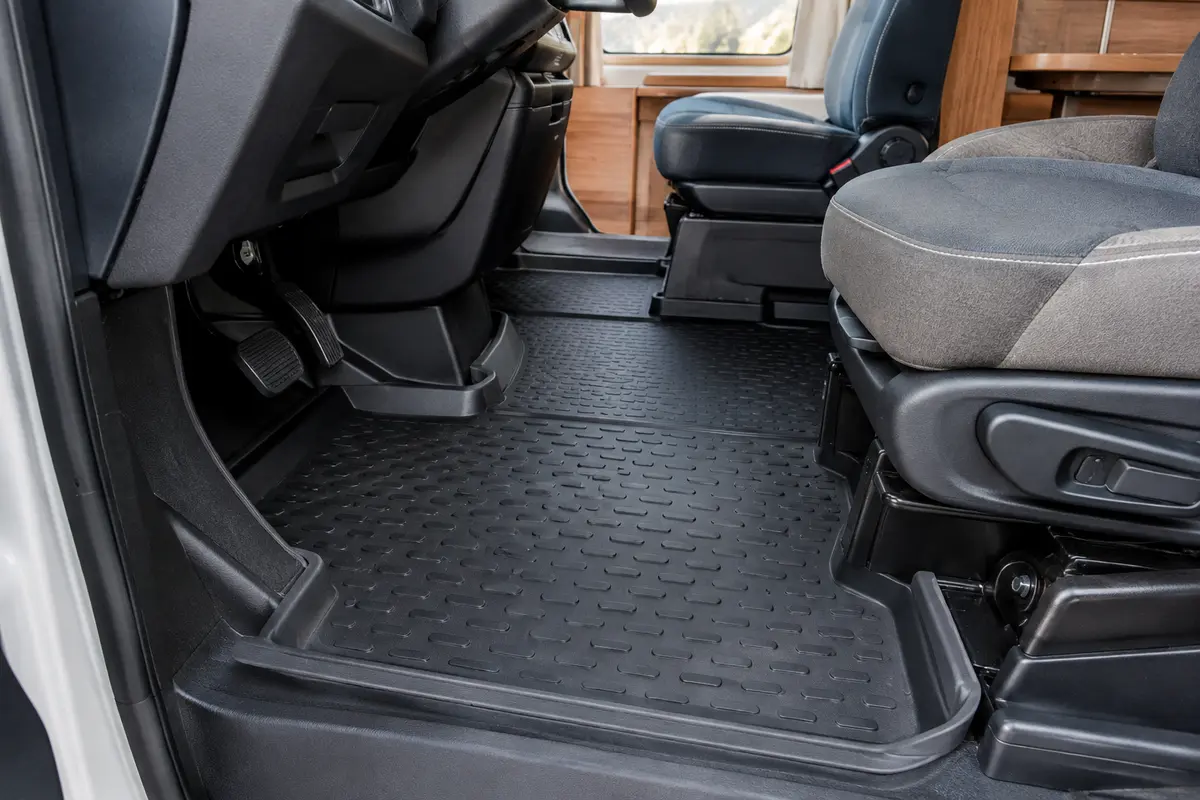 Tapis de sol noir monobloc en caoutchouc avec rebords relevés, posé dans l’habitacle d’un camping-car.