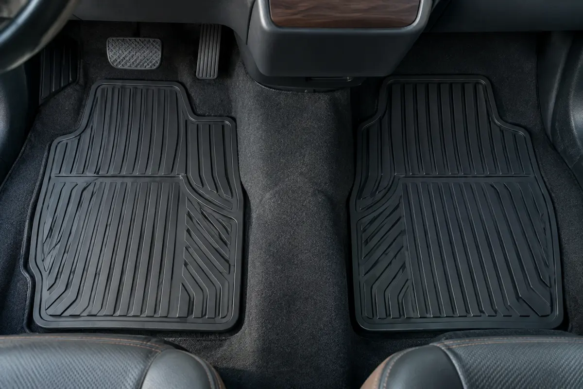 Paire de tapis avant noirs à sillons installés à plat dans un habitacle automobile propre