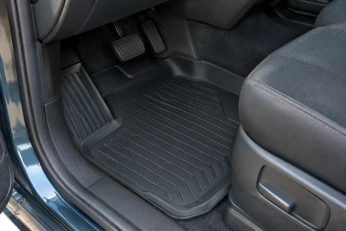 Tapis noirs en caoutchouc ajustés au plancher avant d’un utilitaire, avec rebords relevés et renfort côté conducteur.