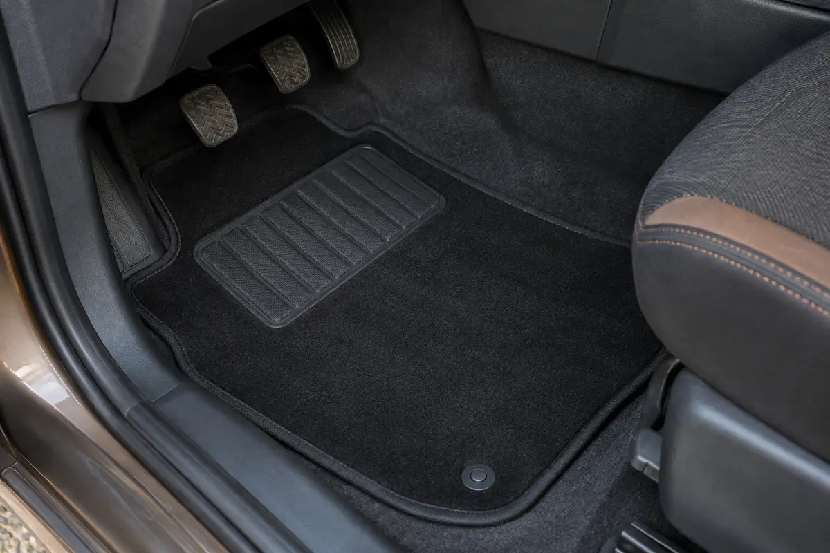 Tapis avant noir en velours avec bordure antidérapante et talonnette renforcée dans un habitacle d’utilitaire