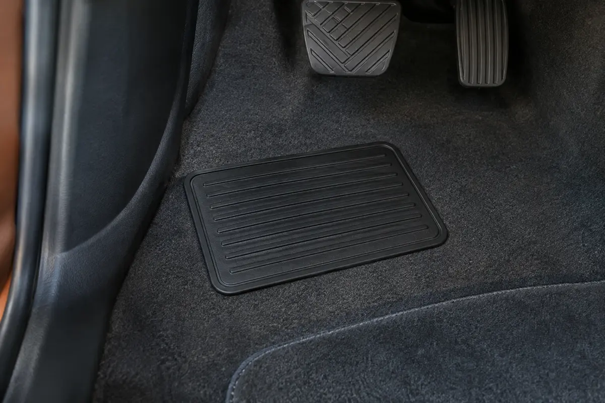 Petit tapis de talon noir en PVC posé près d’un tapis de sol dans un habitacle automobile propre.
