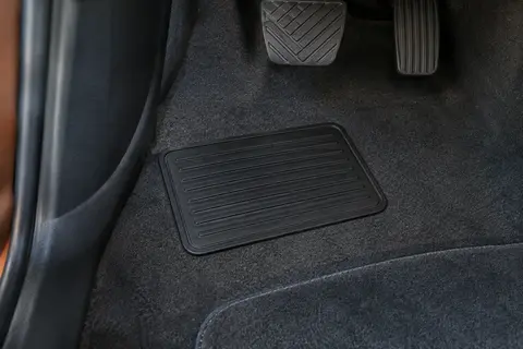 Petit tapis de talon noir en PVC posé près d’un tapis de sol dans un habitacle automobile propre.