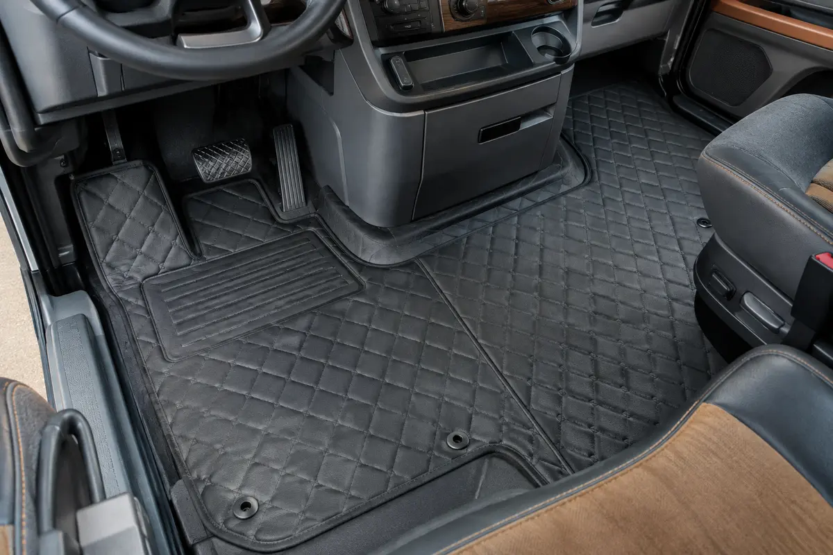 Ensemble de tapis noirs en éco-cuir texturé posé dans la cabine fonctionnelle d’un camion, avec détails des reliefs.