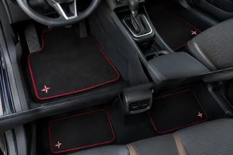 Jeu de quatre tapis auto en moquette noire à bordure rouge, ornés d’une petite étoile brodée rouge et blanche, dans un habitacle propre.
